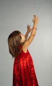 malá holčička v červených šatech s rukama nahoru