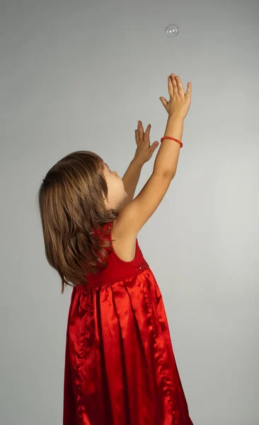 Klein meisje in een rode jurk met handen omhoog — Stockfoto