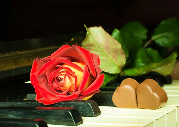 Τριαντάφυλλο και σοκολάτας καρδιές σε ένα πιάνο — Φωτογραφία Αρχείου