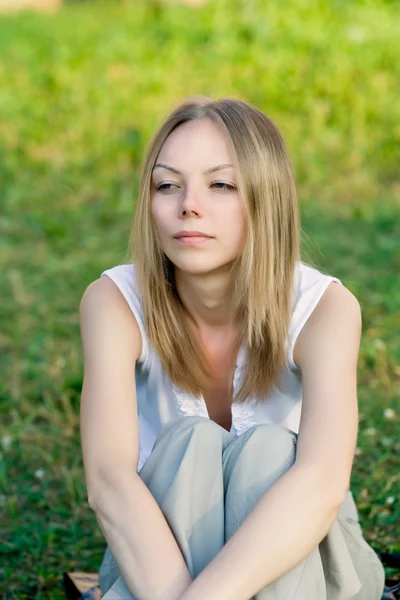 A beautiful young woman sitting in the g — Stock Photo, Image