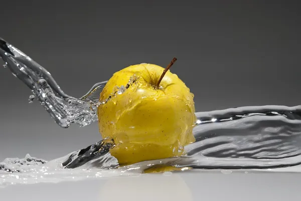 Water splash on yellow apple
