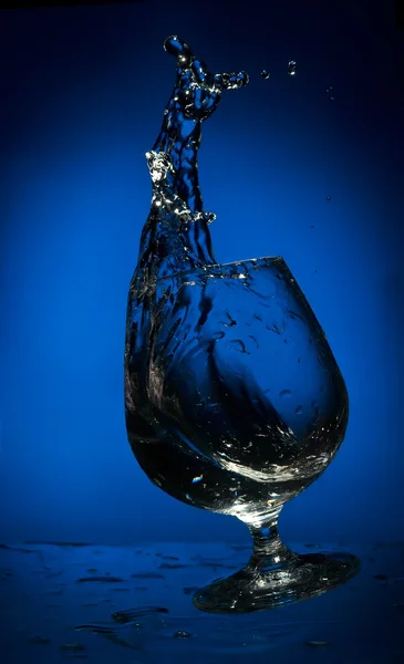 Grote plons van vloeistof in een dalende glas — Stockfoto