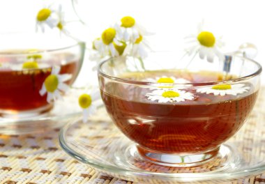 Cups of tea and chamomile blossoms clipart