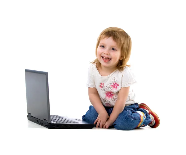 Linda niña sentarse cerca de la computadora portátil —  Fotos de Stock