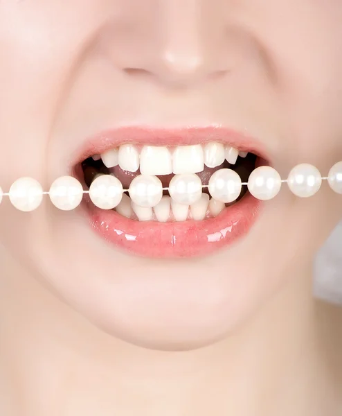 Dentes mordendo em pérolas falsas — Fotografia de Stock