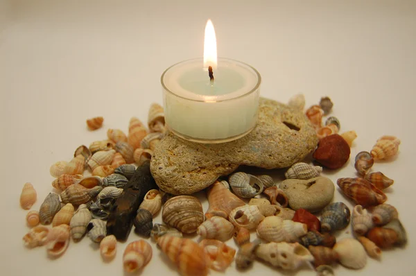 Камни, много маленьких раковин и свечи — стоковое фото