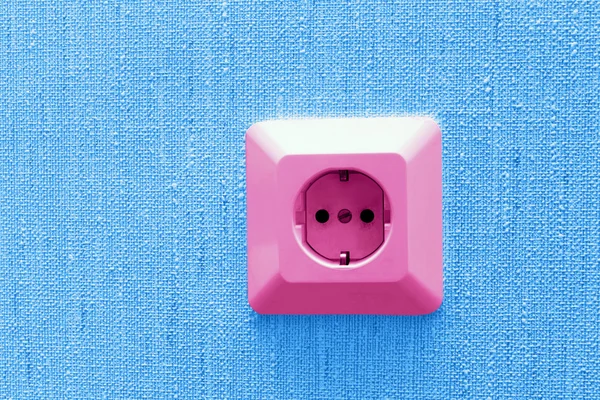 Pink electric socket on blue wall — Stock Photo, Image