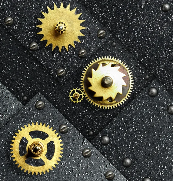 Gold gears against ferrous metal — Stock Photo, Image