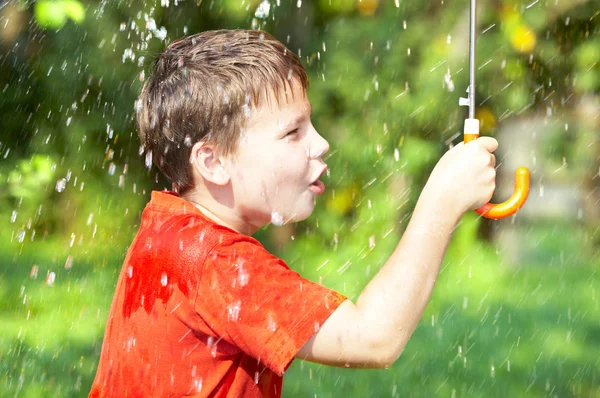 Мальчик под зонтиком во время дождя — стоковое фото