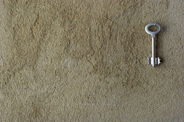 Iron key on a concrete wall — Stock Photo, Image