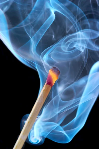 Photo of a burning match in a smoke on a — Stock Photo, Image