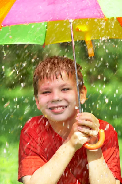 Çocuk bir yağmur sırasında bir şemsiye altında — Stok fotoğraf