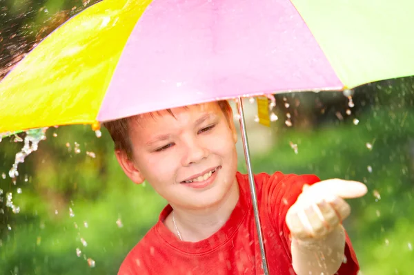 Garçon sous un parapluie sous une pluie — Photo