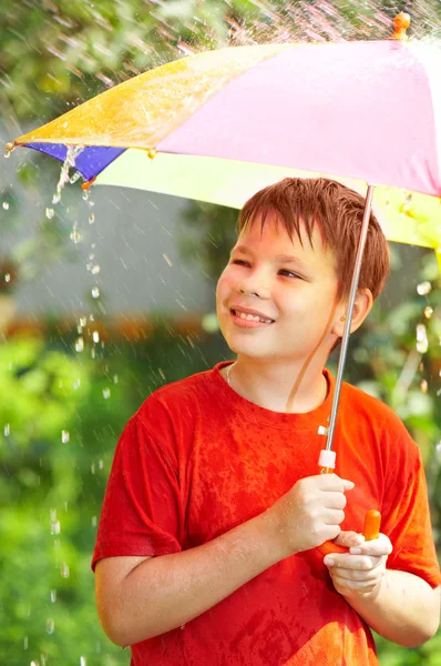 Menino sob um guarda-chuva durante uma chuva — Fotografia de Stock