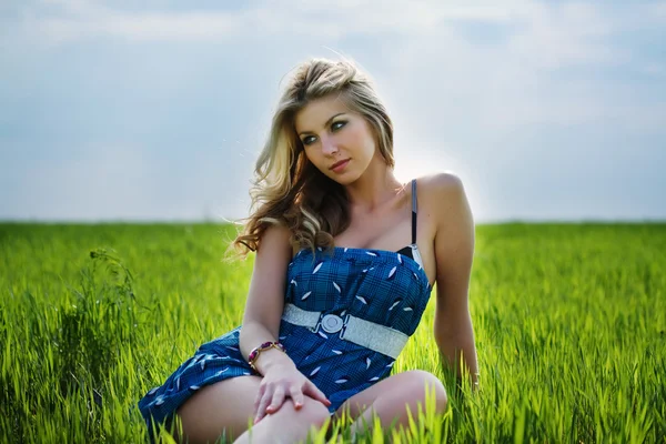 Beautiful woman sitting in the field — Stock Photo, Image