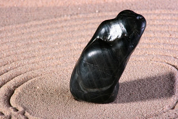 Black stone is on sand — Stock Photo, Image