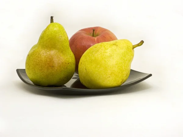 Тарілка з жовтими грушами і яблуком — стокове фото