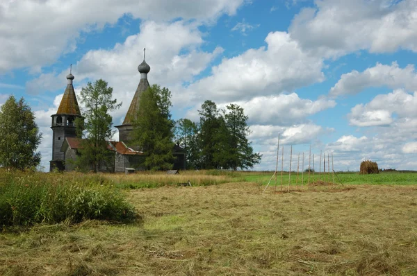 Feld mit Heuhaufen und Holzkirche — Stockfoto
