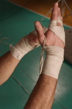 Male boxer putting on white wrist wraps clipart