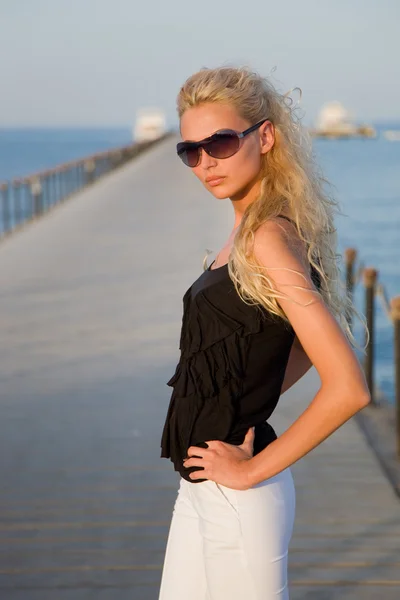 Blond meisje met bronzen tan op een pier — Stockfoto