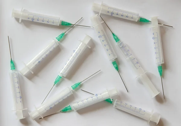 Injekční stříkačky s jehlami na bílém pozadí — Stock fotografie