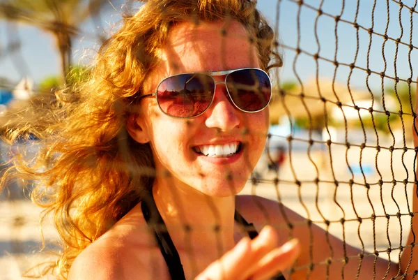 Gelukkig vrouw achter de volleybal net — Stockfoto