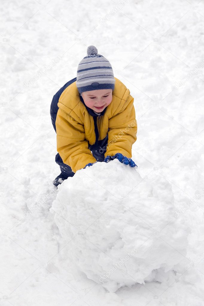 The boy rolls snow whom