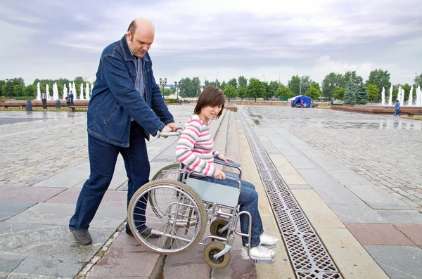 Мужчина толкает женщину в инвалидном кресле — стоковое фото
