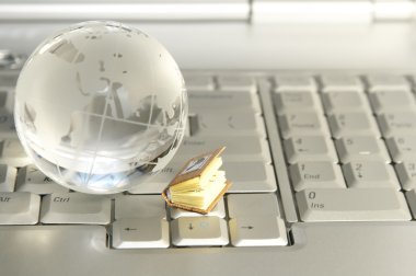 Little book and glass globe on laptop clipart