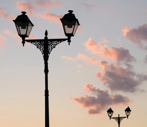 Two street lamp silhouettes on sky backg — 图库照片