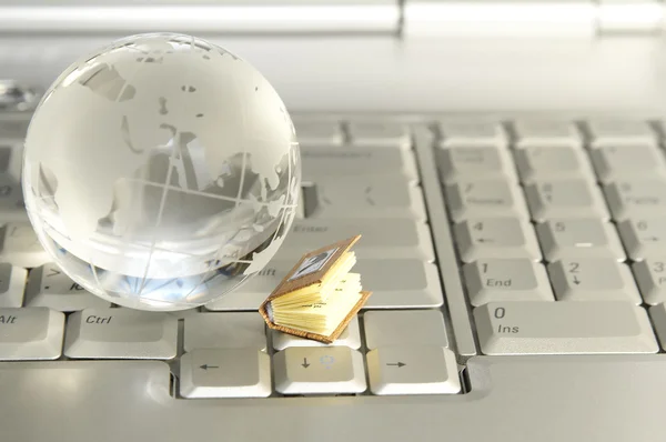 Little book and glass globe on laptop — Stock Photo, Image