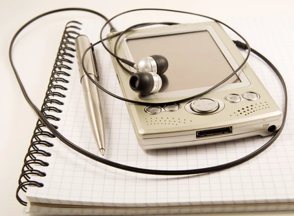 Caneta e PDA com fones de ouvido no notebook — Fotografia de Stock