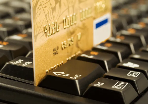 Tarjeta de crédito de oro en el teclado del ordenador — Foto de Stock