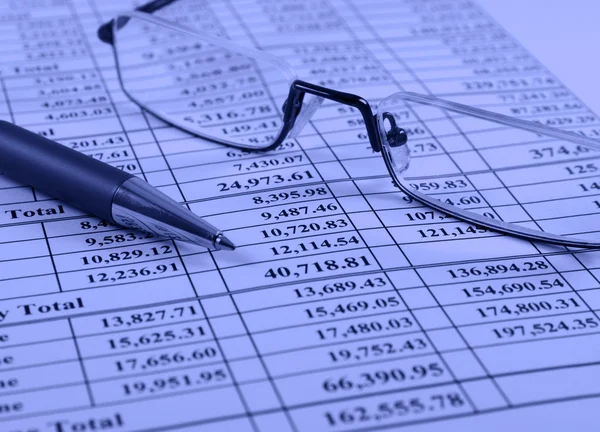 Pen and glasses on financial report — Stock Photo, Image