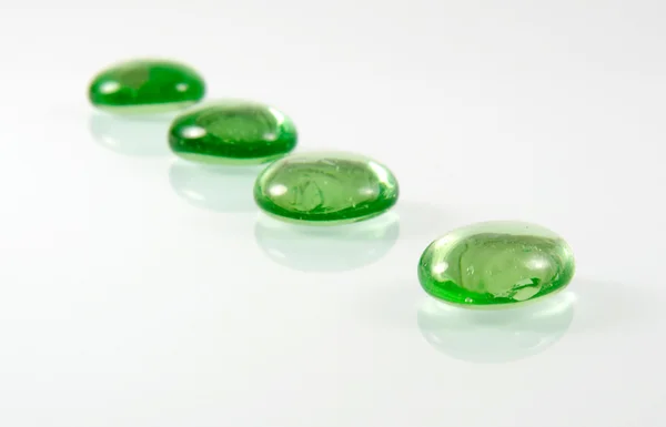 Four green glass pebbles in row — Stock Photo, Image