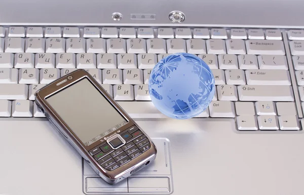 Telefon komórkowy i szkło globe na laptopie — Zdjęcie stockowe