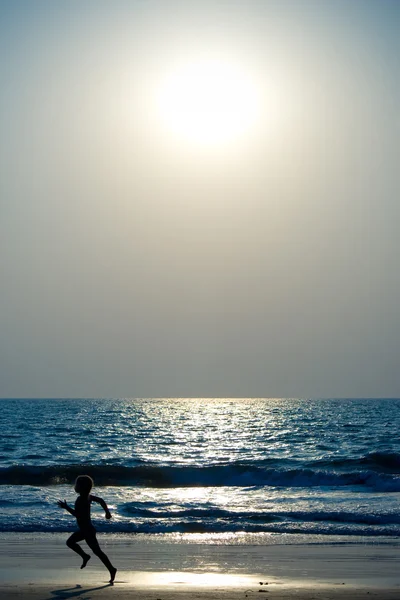 Junge rennt an den Strand Stockbild