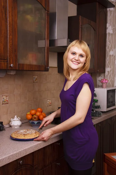 Frau schneidet heißen Apfelkuchen in Küche — Stockfoto