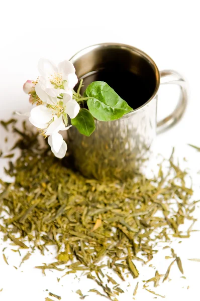 stock image Cup of tea with flower and tea leafs