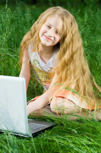 Petite fille drôle assis avec ordinateur portable ou — Photo