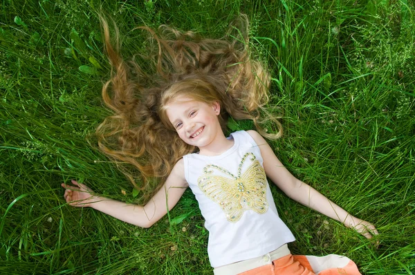 Uśmiechnięta dziewczynka w zielonej trawie — Zdjęcie stockowe