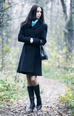 Slim brunette woman walking in a park clipart