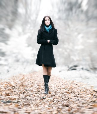 Slim brunette woman walking in a park clipart