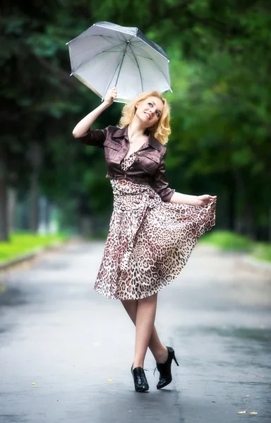 Şemsiye ile yürüyen genç bir kadın — Stok fotoğraf
