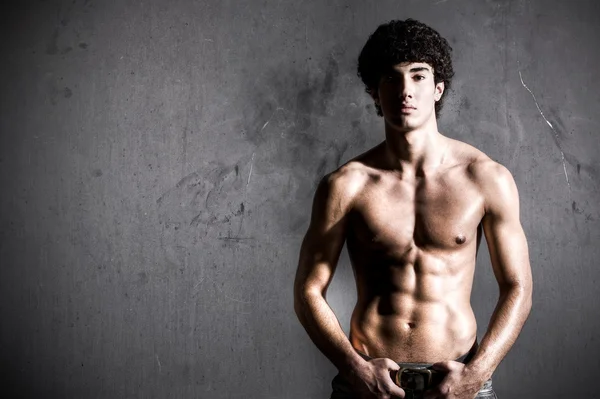 Молодой мускулистый мужчина на фоне стены — стоковое фото