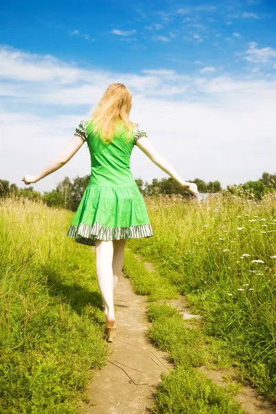 Jeune femme heureuse marchant dans un champ — Photo