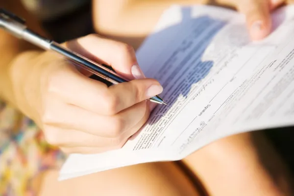 Ung kvinna underteckna ett dokument — Stockfoto
