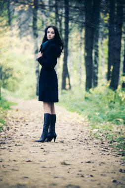 Slim brunette woman walking in a park clipart