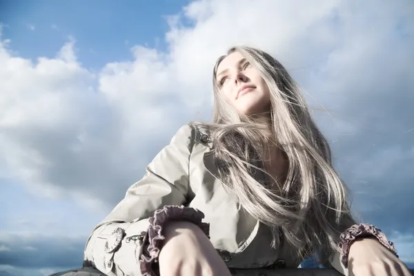 Ung blond kvinna på blå himmel bakgrund — Stockfoto
