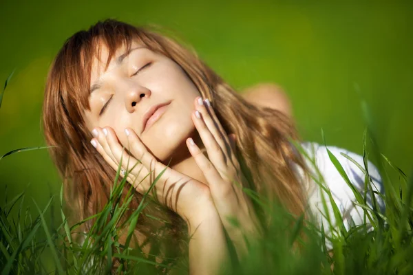 Νεαρή γυναίκα ξαπλωμένη στο γρασίδι — Φωτογραφία Αρχείου